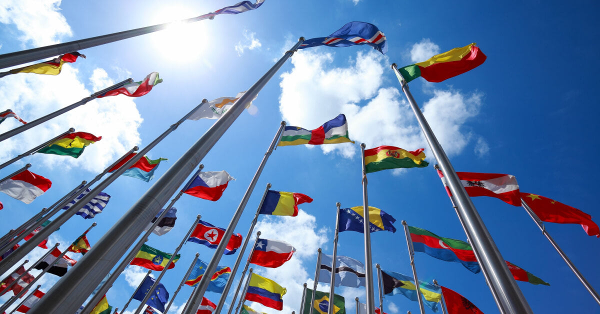 Flags of many nations of the world are flying in blue sky